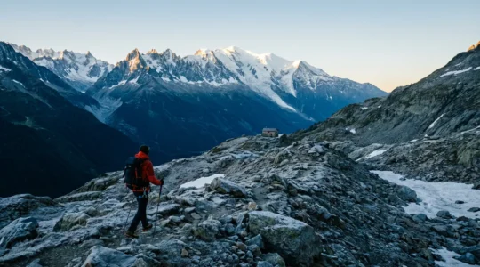 Alpiniste débutant contemplant le Mont Blanc depuis un sentier d'approche, avec équipement de montagne et carte topographique