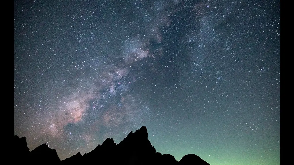 Ciel étoilé avec la Voie lactée visible au-dessus des sommets montagneux dans l'obscurité totale