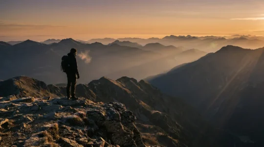 Randonneur contemplant un panorama montagneux à haute altitude avec effet de lumière dorée suggérant la raréfaction de l'air